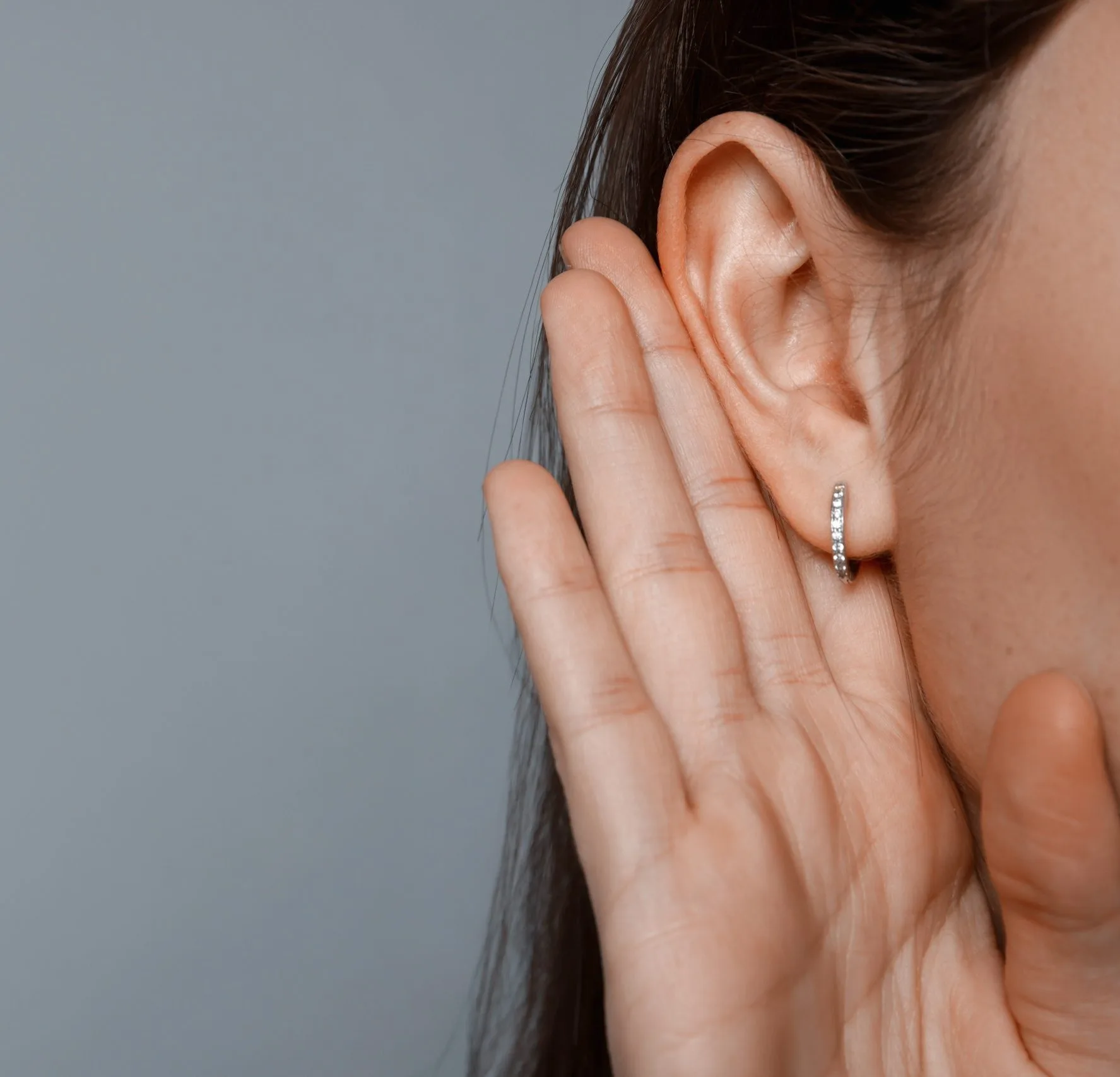 Close-up of a woman cupping her hand behind her ear