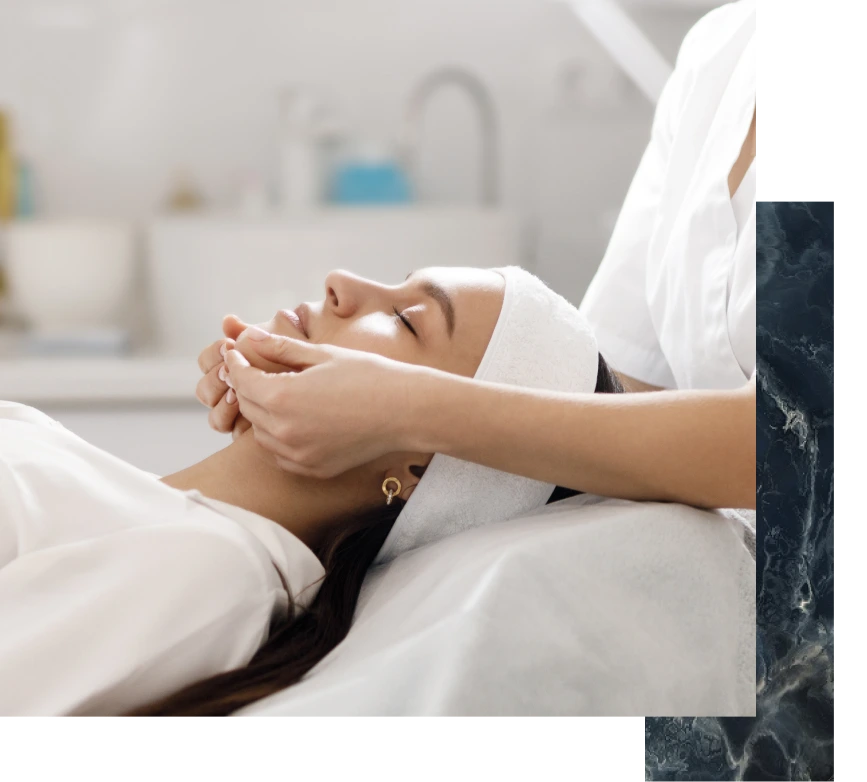 Clinician's hands massaging patient's wrapped face in medical spa setting