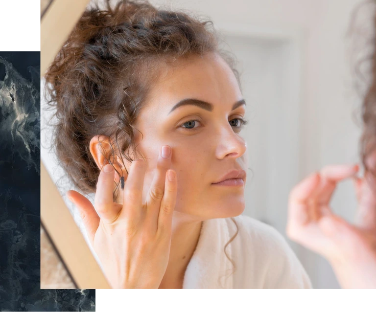 Woman examining her cheek in mirror during skincare consultation