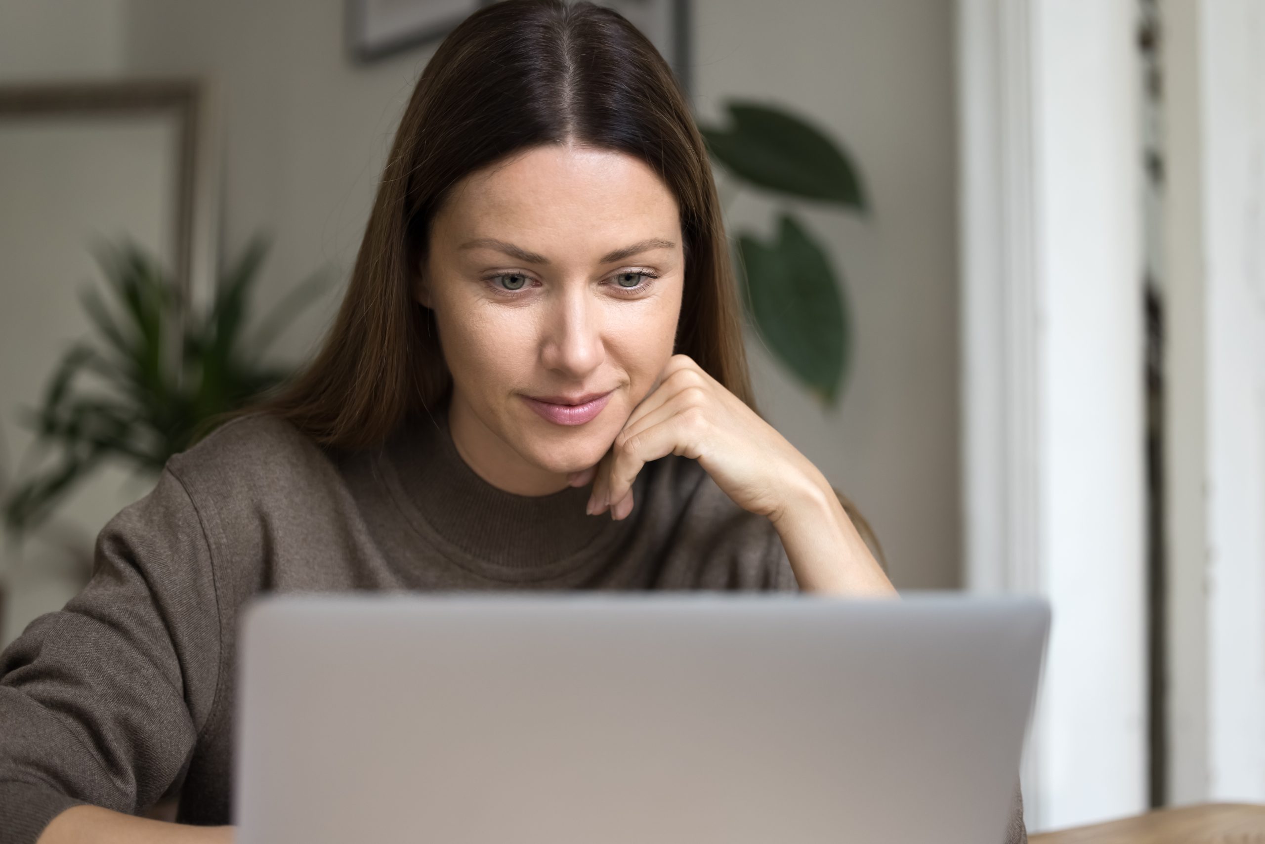 Woman reviewing information on a laptop while researching plastic surgery options