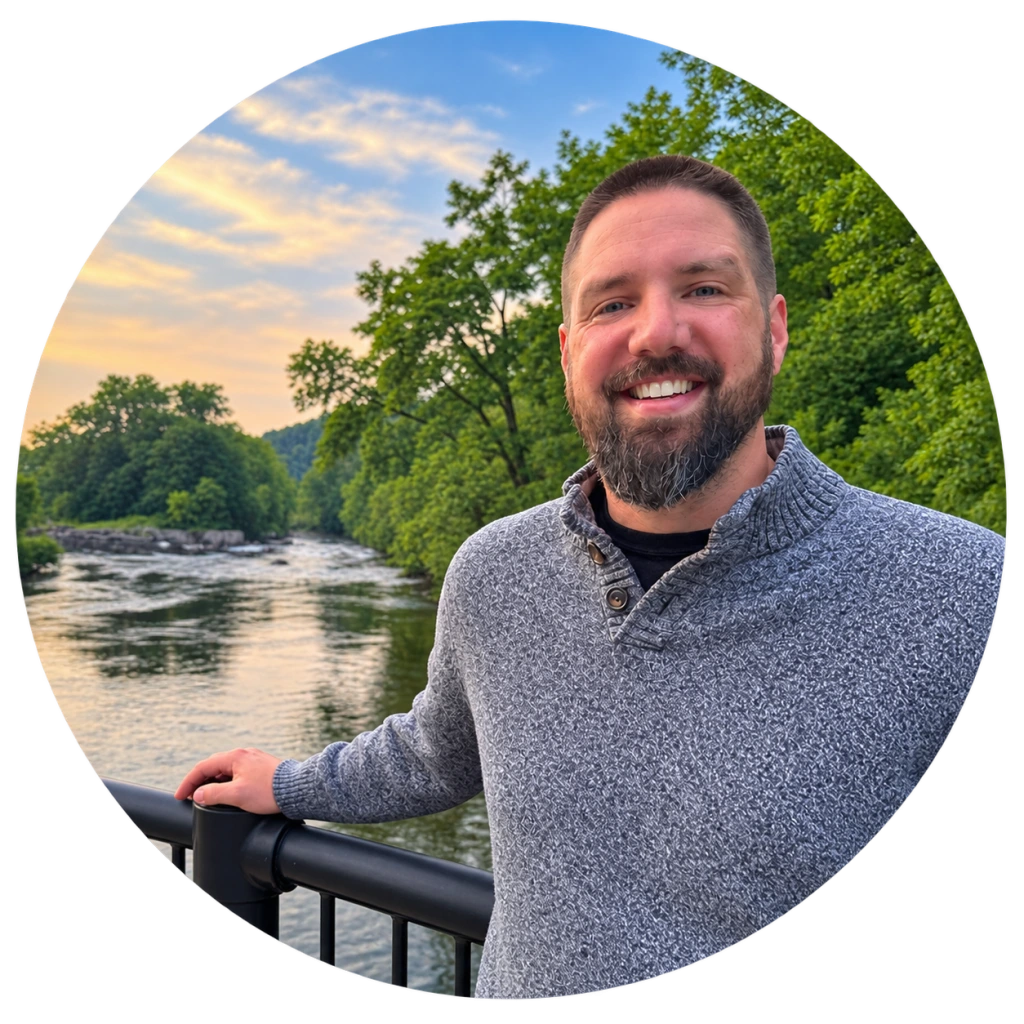 Keith Wasserboehr, therapist at Insights Psychological Services, smiling outdoors by a river with forested hills in the background