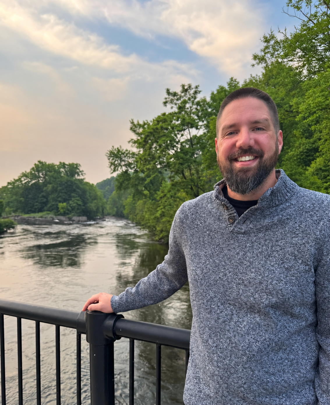 Keith Wasserboehr, Therapist, smiling at a river overlook surrounded by green trees