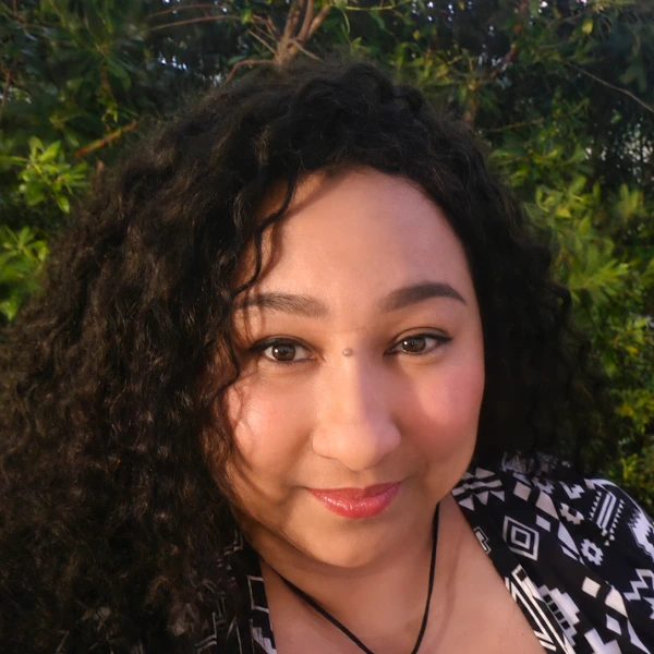 Dr. Samantha Jackson, woman with curly dark hair wearing patterned black and white top against green background