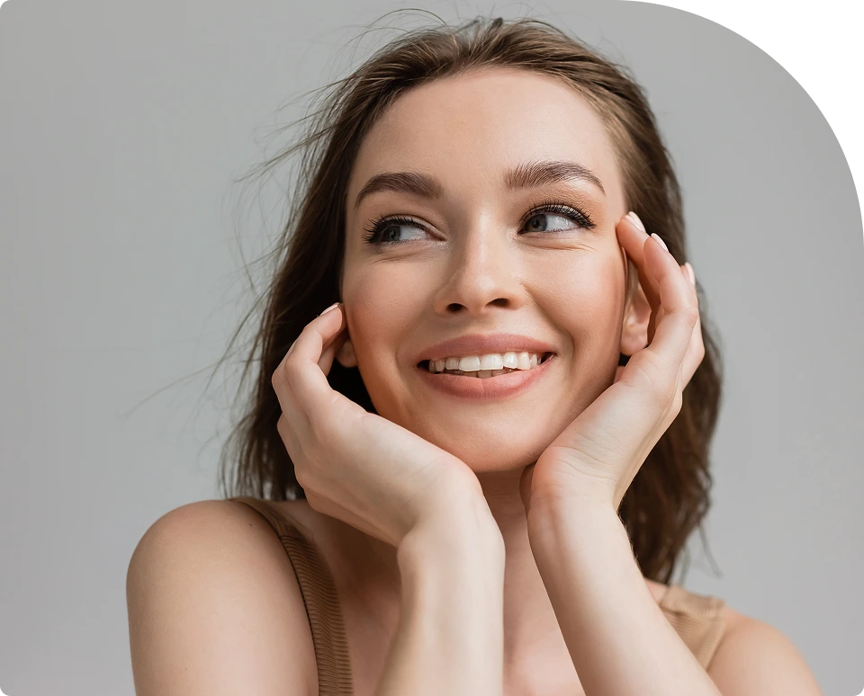 Woman with smooth, glowing skin smiling while cupping her face with both hands