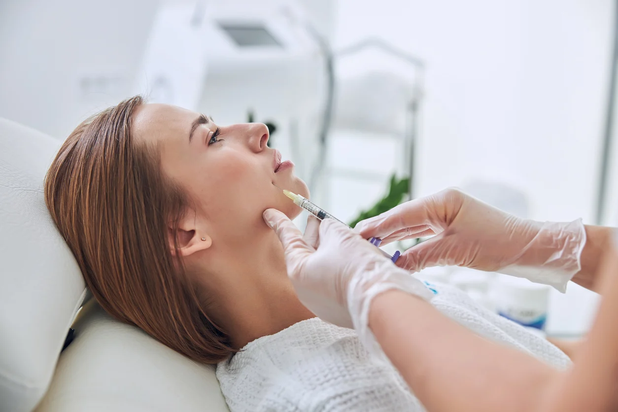 Gloved injector placing filler along a patient’s chin and jawline