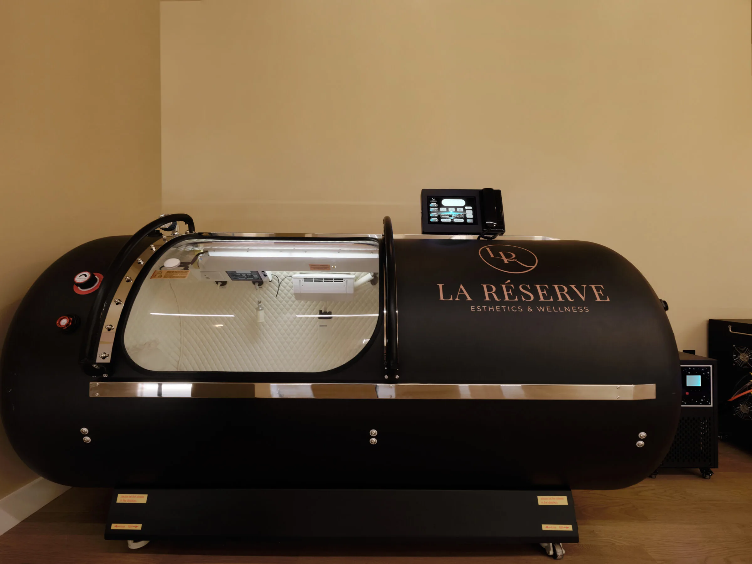 Hyperbaric oxygen chamber at La Réserve Aesthetics and Wellness with transparent acrylic door and control panel