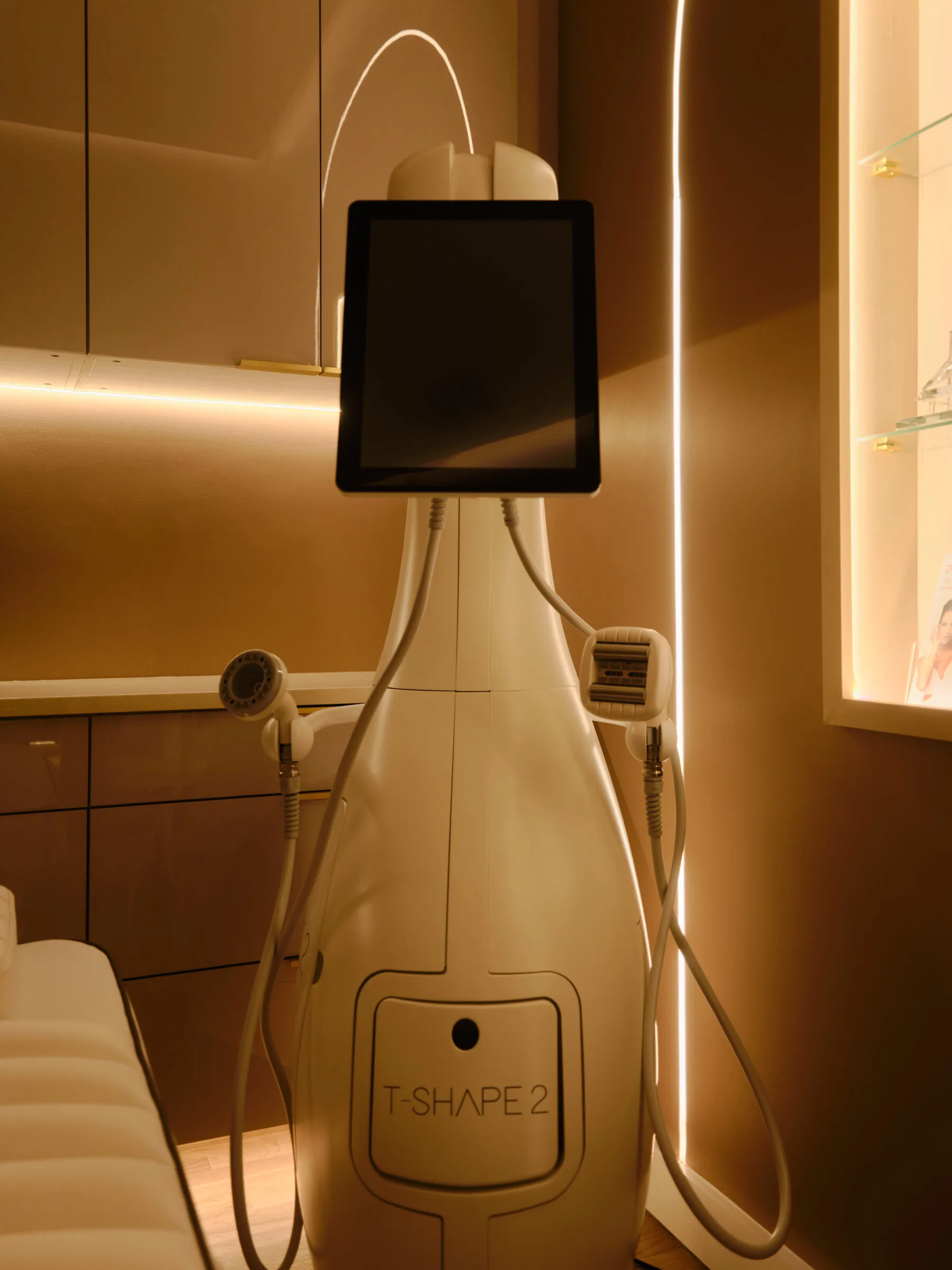 T-Shape 2 aesthetic treatment device with touchscreen display in a warm-toned treatment room at La Reservé Aesthetics and Wellness
