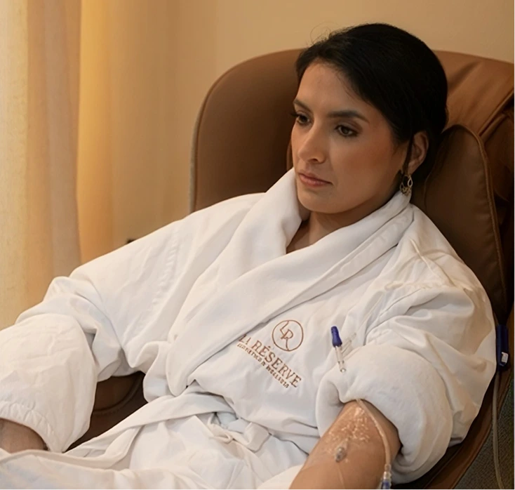Patient receiving Lipo+ treatment at La Reservé Aesthetics, seated in medical chair wearing branded robe