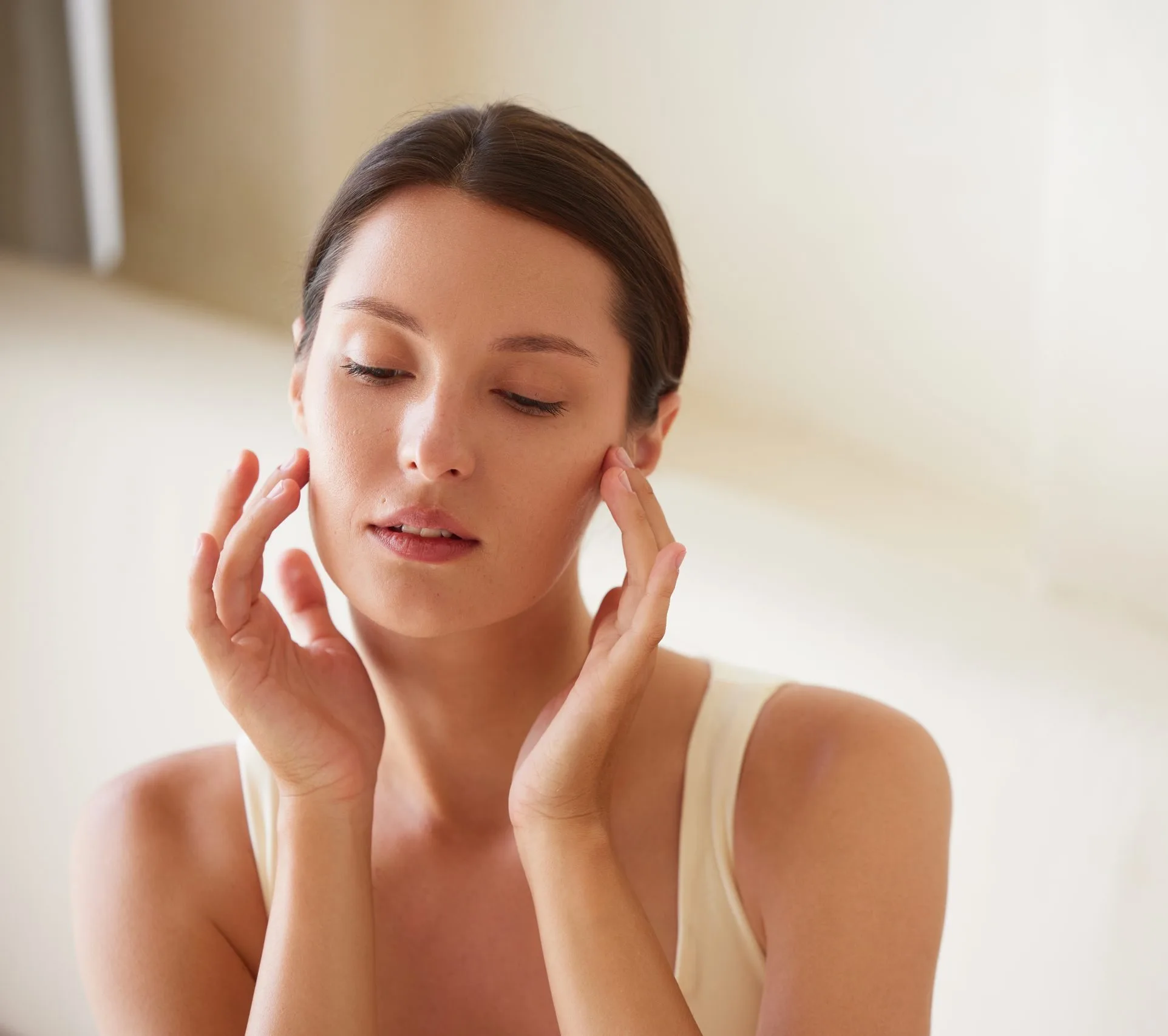 Woman touching face with both hands, eyes closed