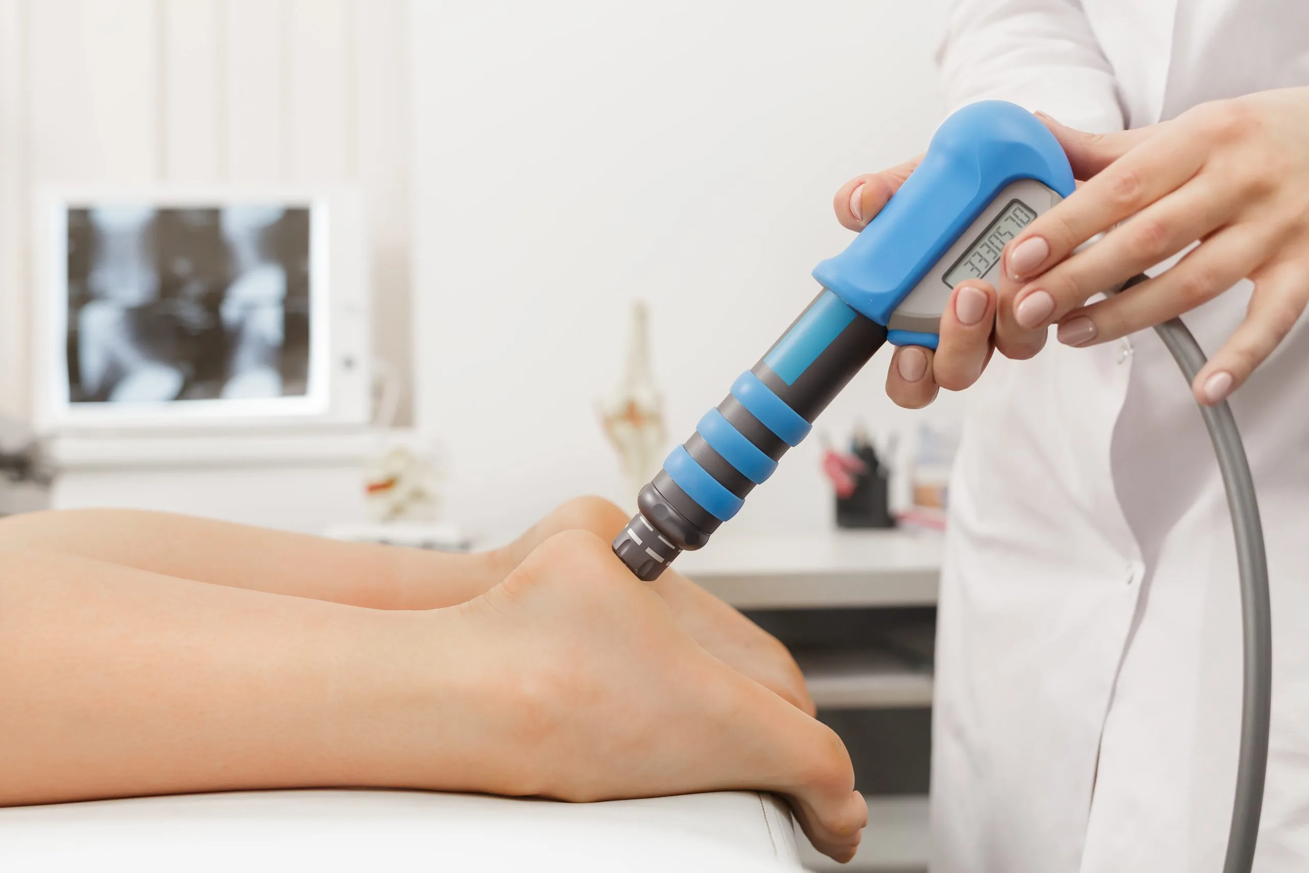 Podiatrist using handheld ultrasound device on patient's foot in clinical setting
