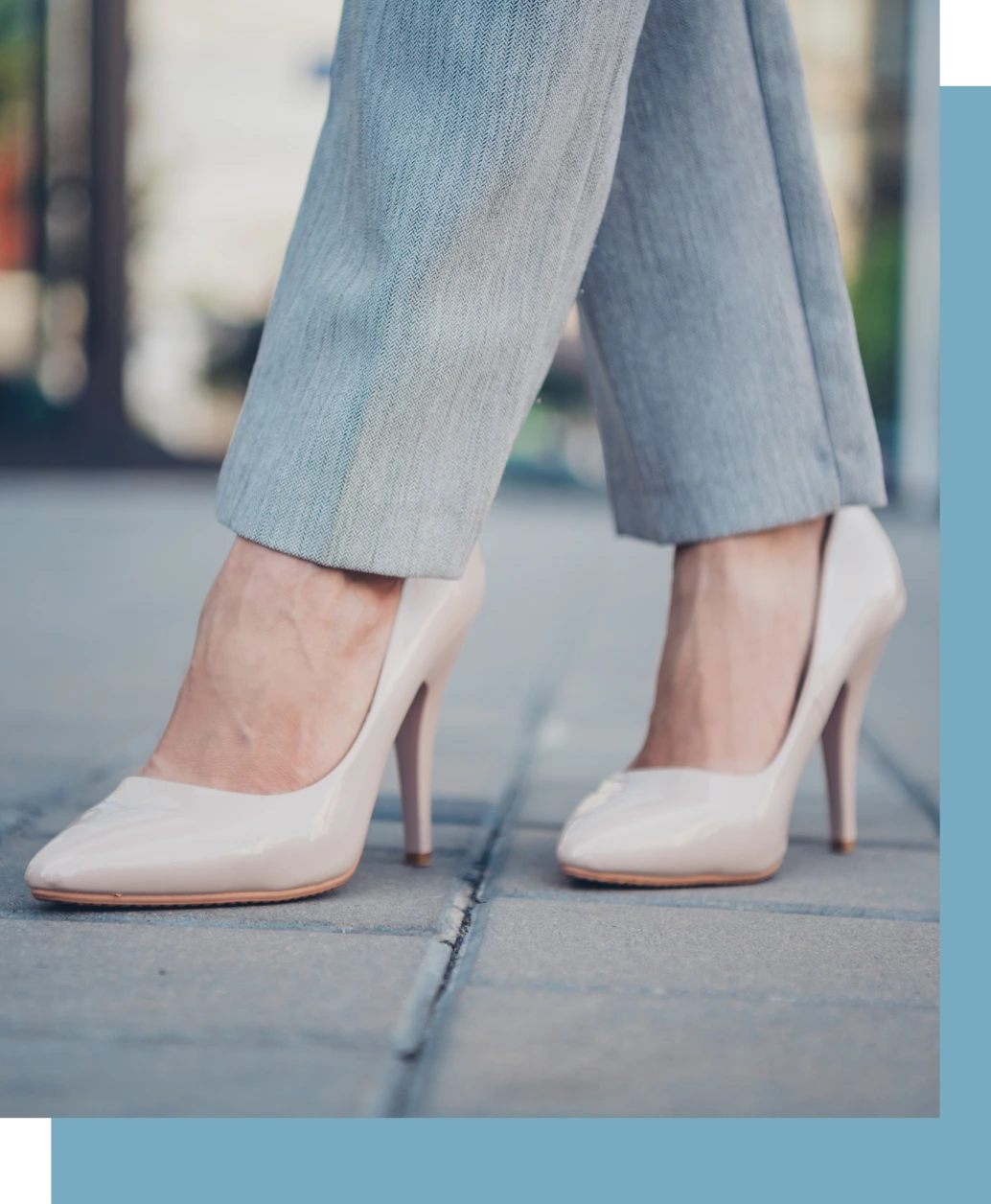 Woman wearing white heels and gray pants walking on a sidewalk
