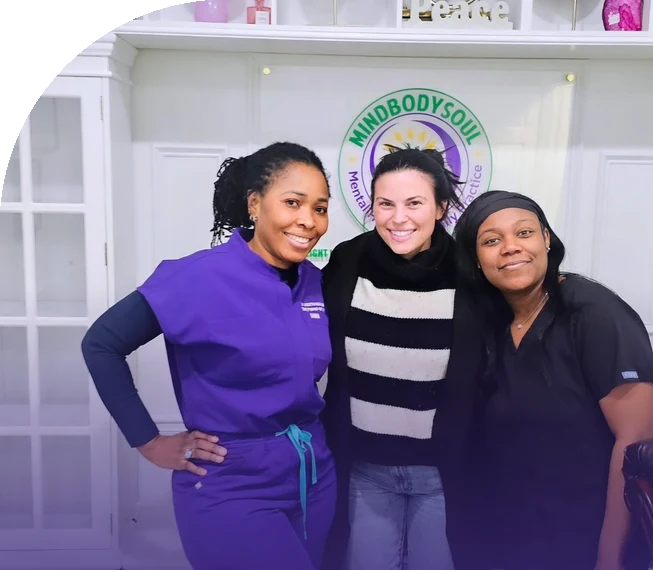 Dr. Judith Ngulefac and the MindBodySoul team in front of the practice logo