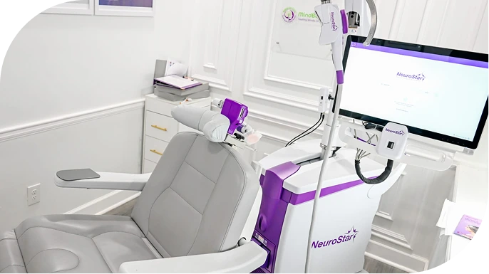 Spravato treatment room with gray patient chair, purple and white medical equipment, monitor, and delivery system
