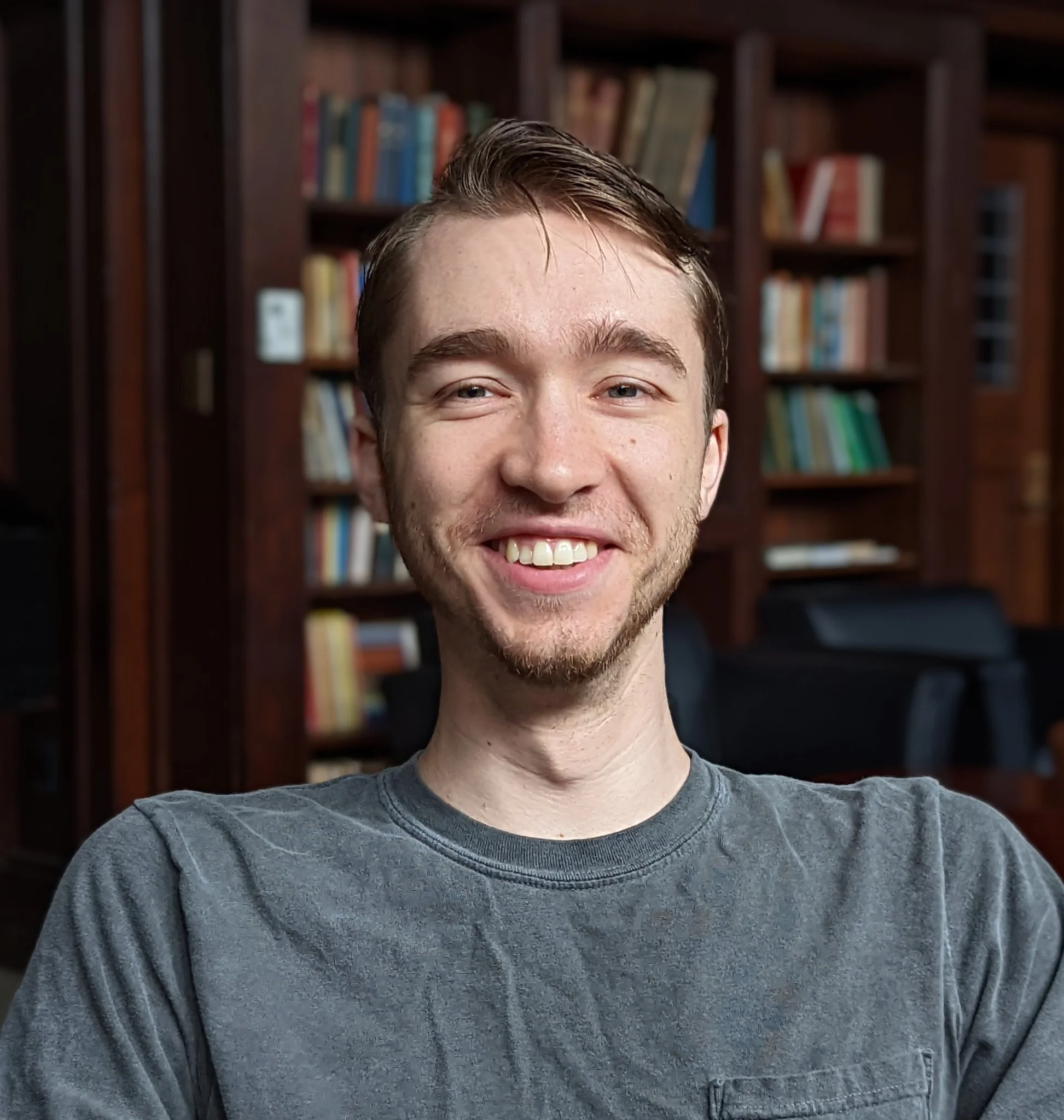 Man smiling at camera in front of a bookshelf