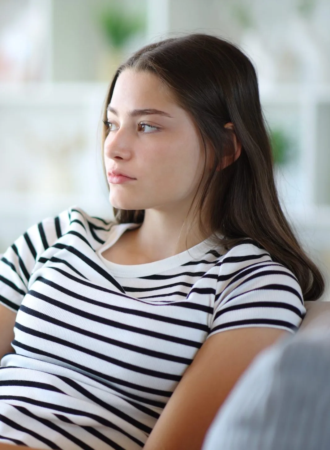 Woman in striped shirt looking downward with a pensive expression