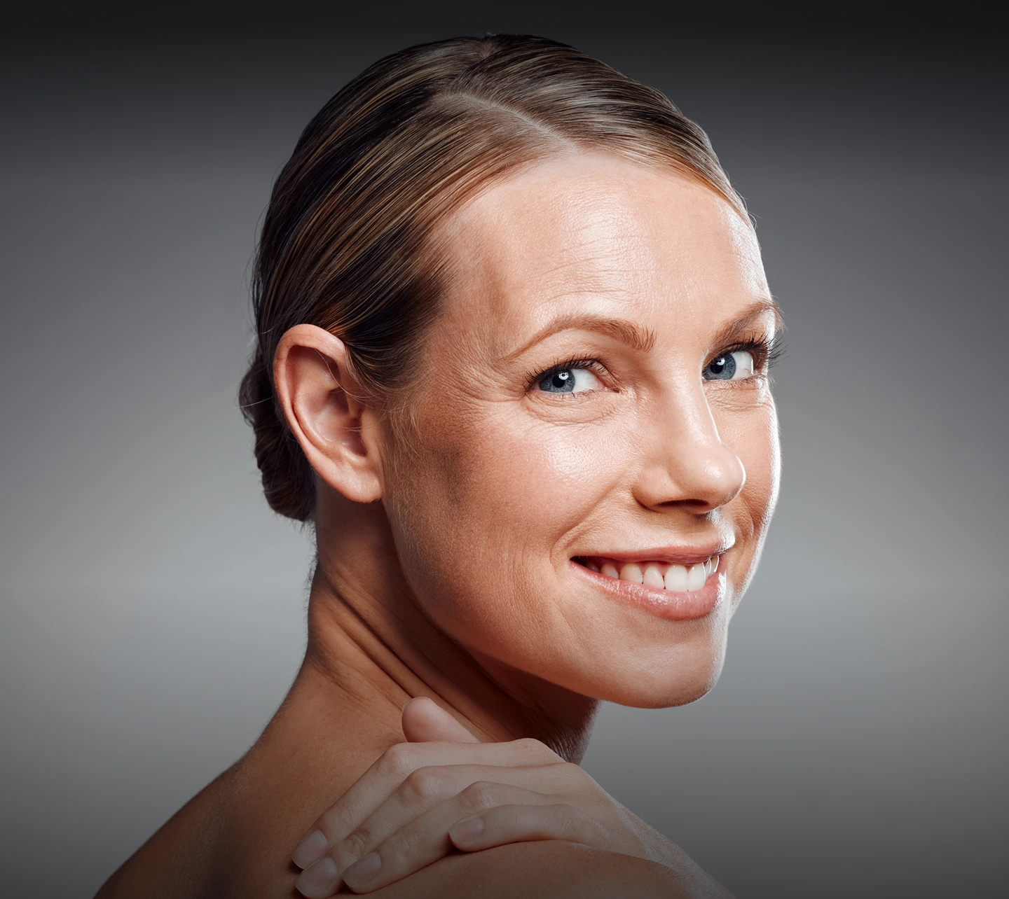 Woman smiling at camera with glowing skin and visible facial contours