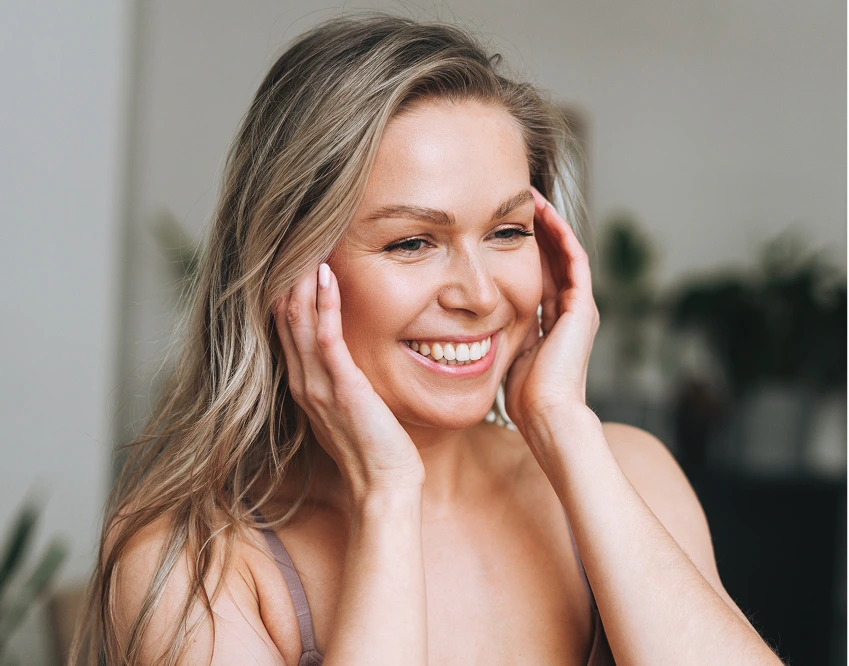 Woman smiling with hands framing her face, displaying radiant skin