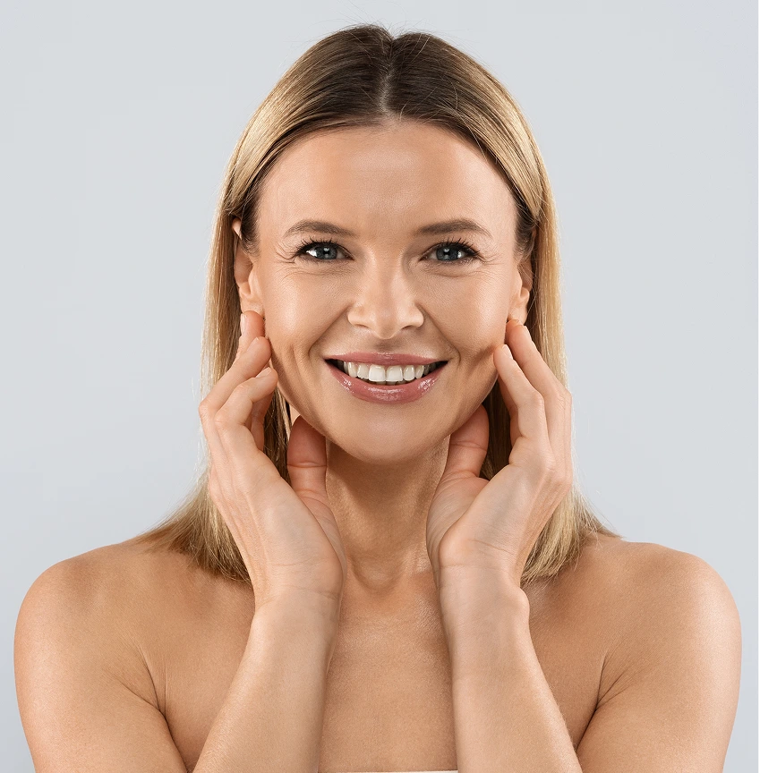 Woman with glowing skin smiling while touching her face