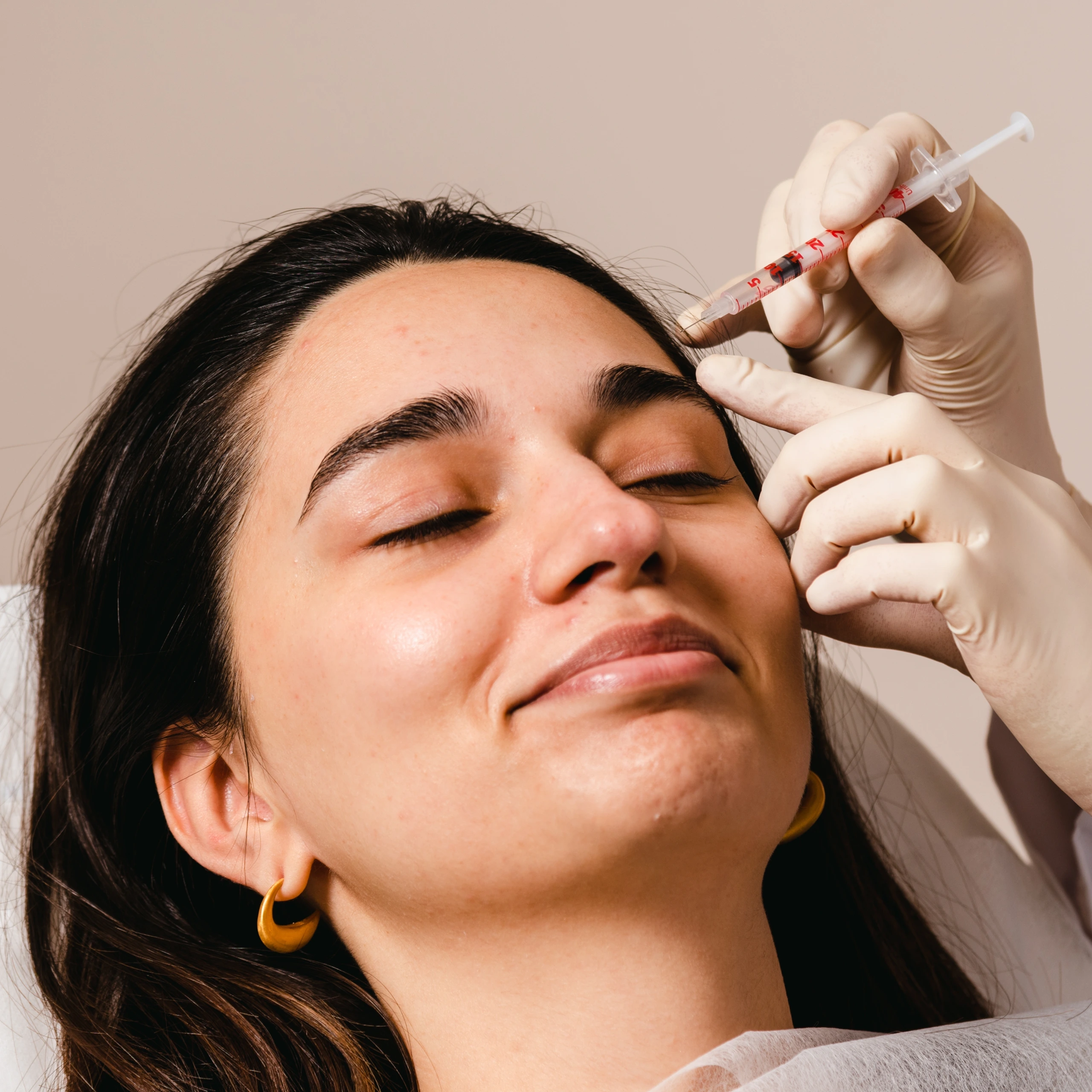 Clinician administering a dermal filler injection to a patient's forehead