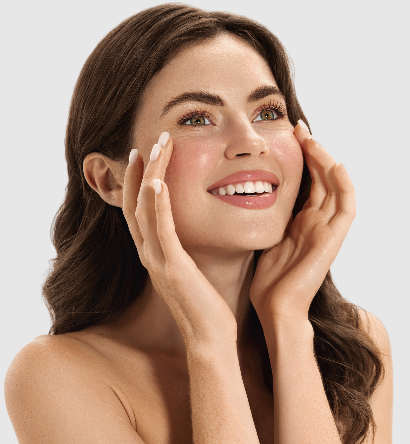 Woman with full eyebrows touching her face, smiling toward camera