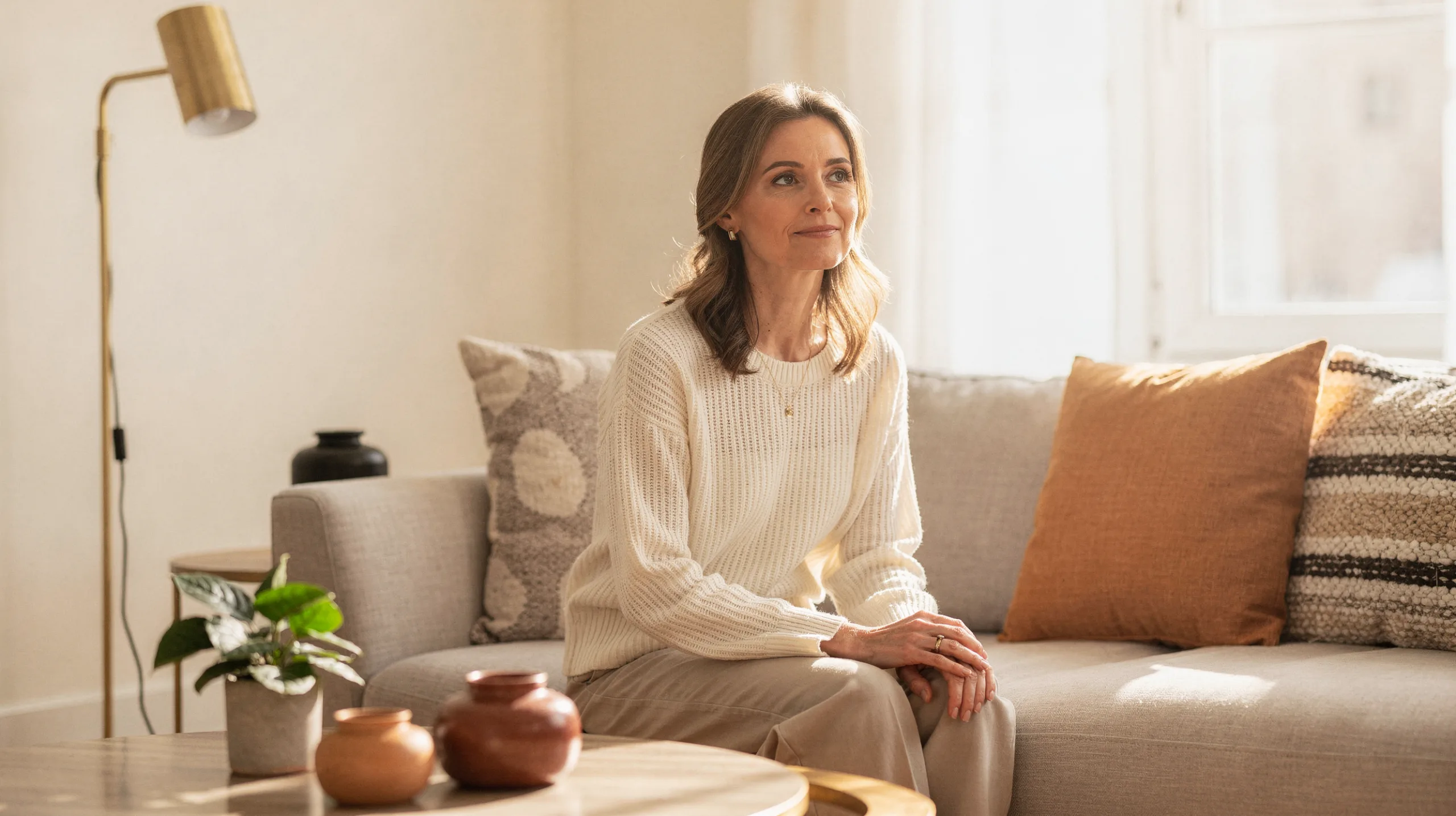 Woman sitting calmly in a sunlit living room, conveying hope and compassionate psychiatric care in Olathe, KS