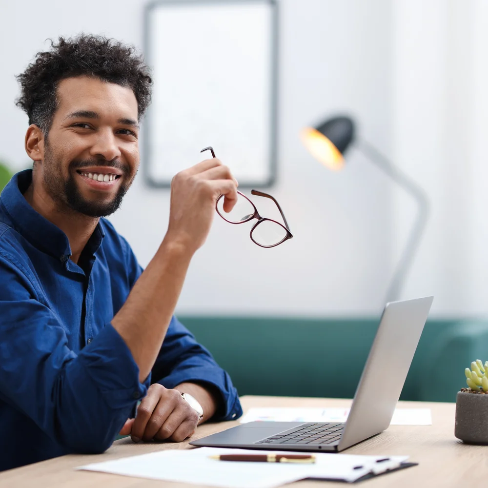 Man smiling at a desk with a laptop during a visit