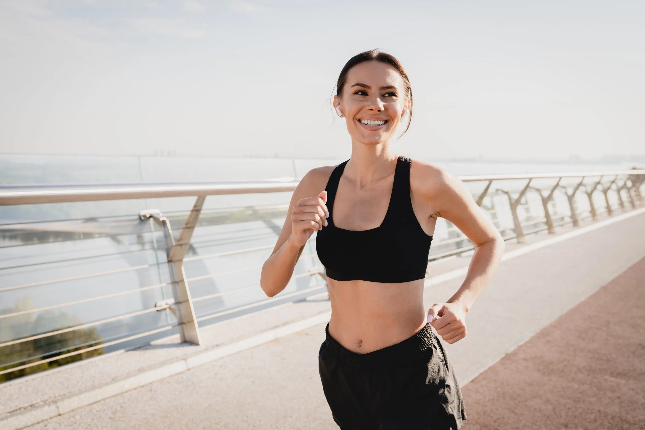 Woman jogging along a seaside promenade, smiling while running