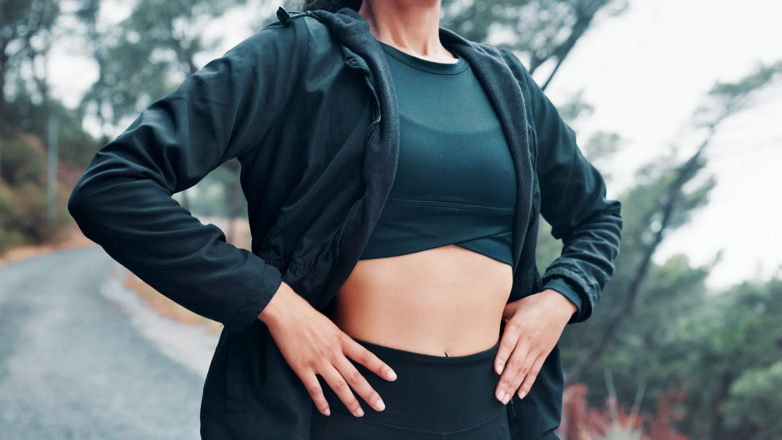 Person in athletic wear touching their abdomen outdoors