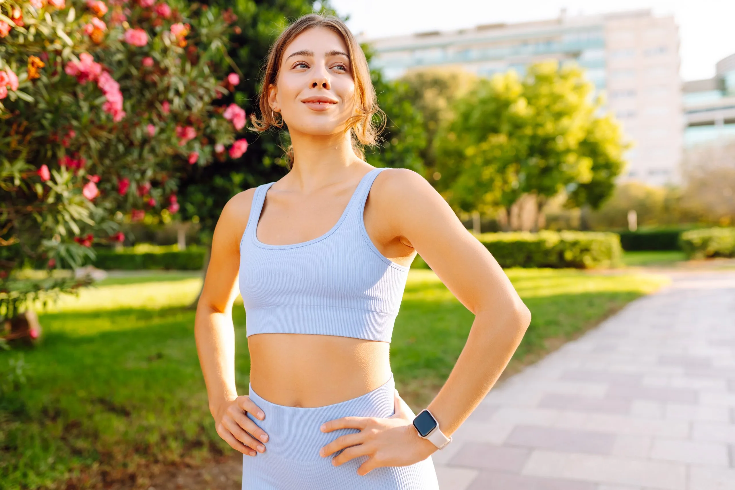 Athletic woman in workout clothes standing in a garden at sunset