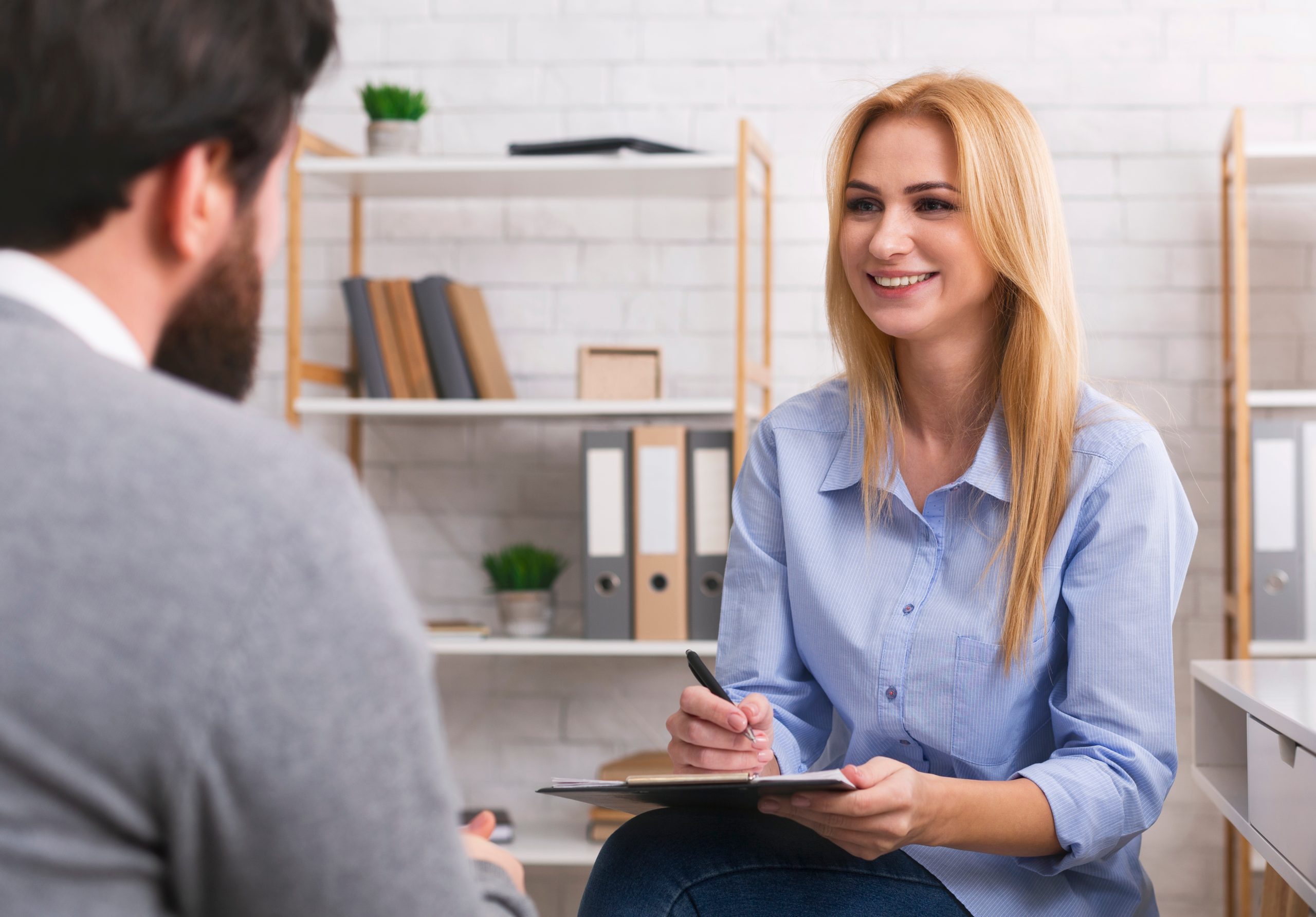 Healthcare provider taking notes while smiling at patient during consultation in bright office