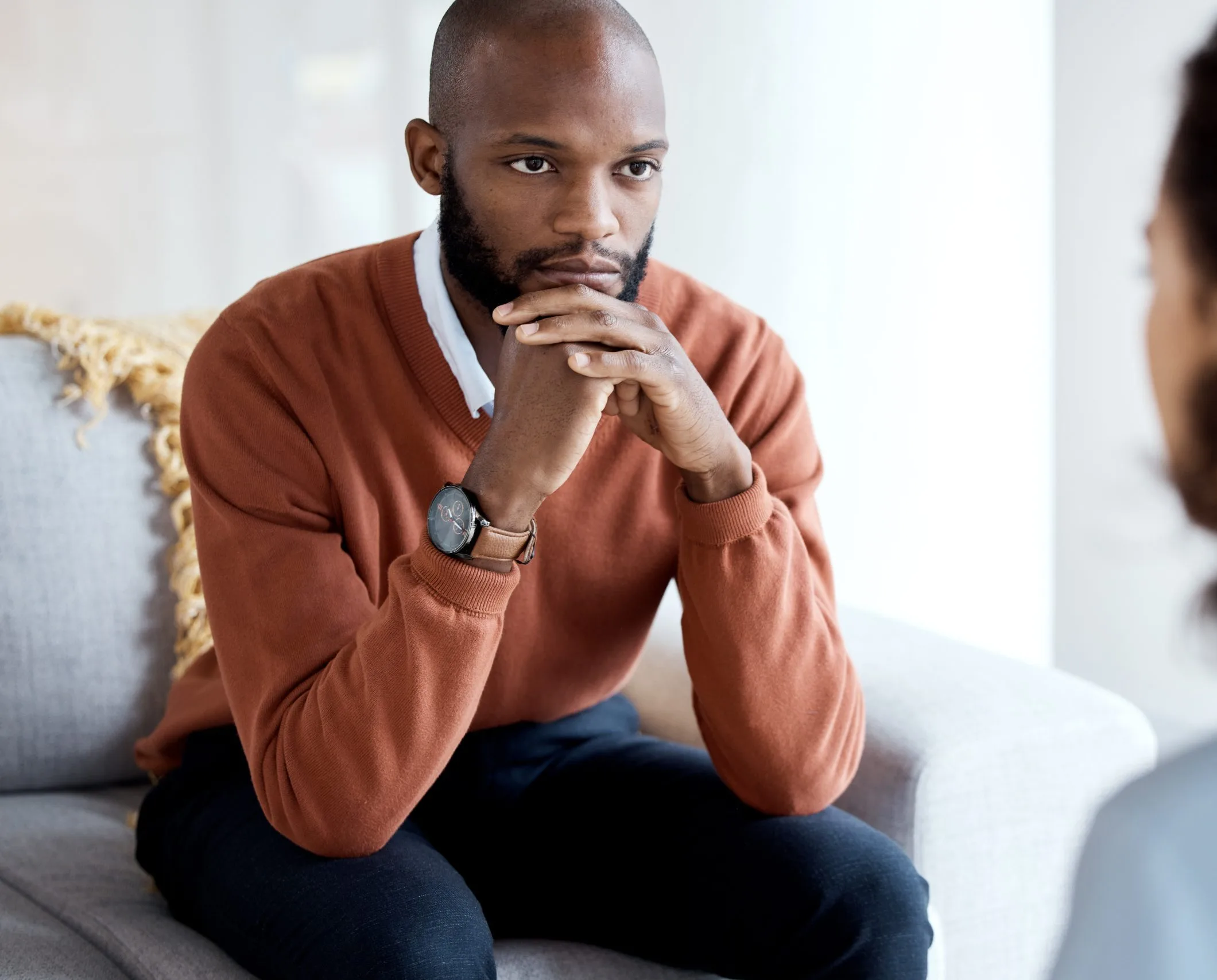Man in rust sweater listening thoughtfully during counseling conversation
