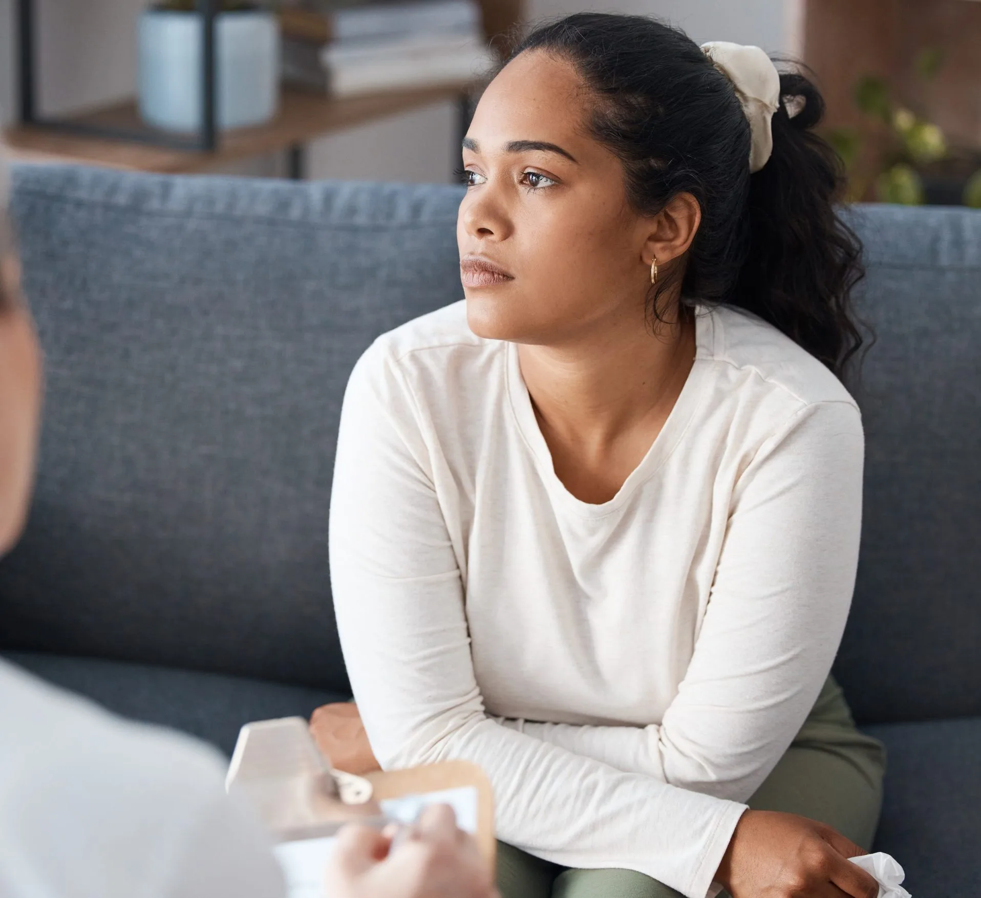 Woman looking thoughtful while seated on couch during therapy session