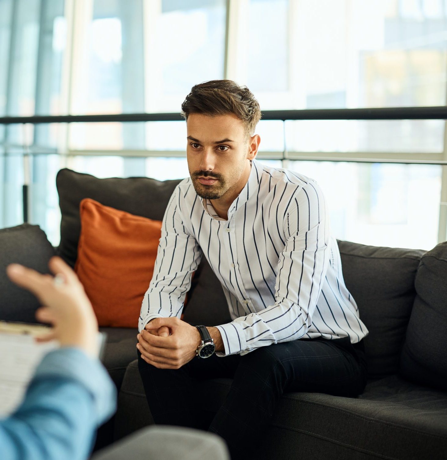 Man in striped shirt listening attentively during conversation in modern office with city view