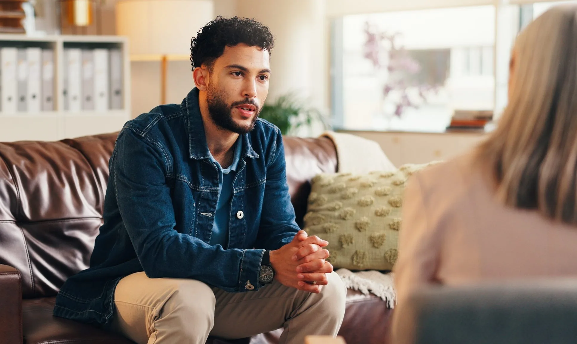 Man in denim shirt speaking with therapist during counseling session