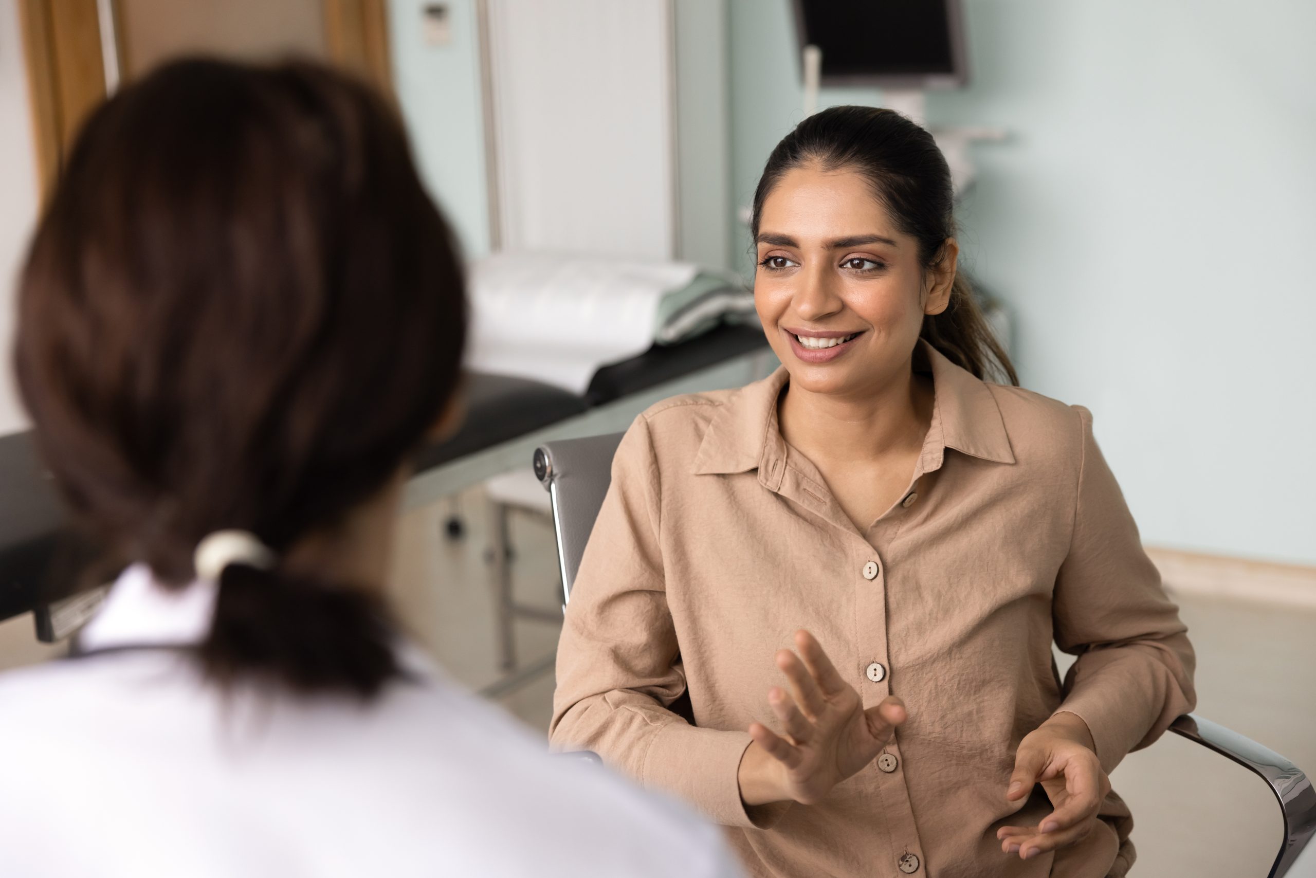 Female healthcare provider smiling while speaking with a patient in a medical office setting