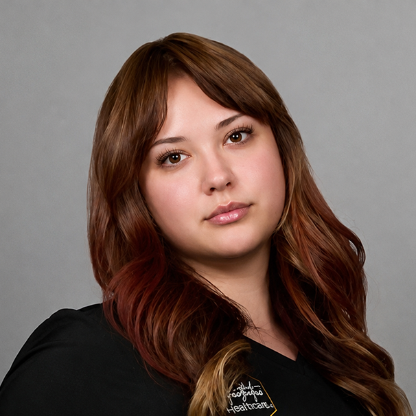 Woman with long brown hair wearing black healthcare uniform against gray background