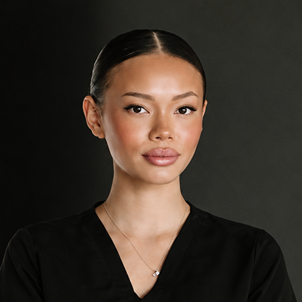 Professional headshot of a woman wearing black scrubs against a dark background
