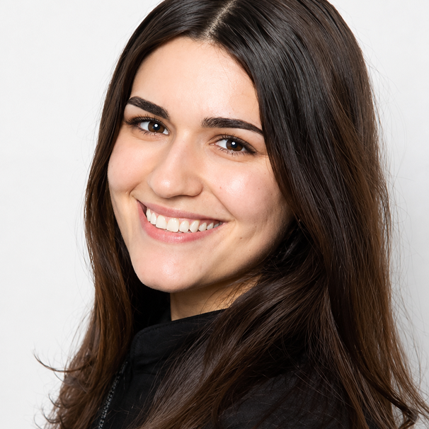 Woman with dark hair smiling, displaying bright teeth against white background