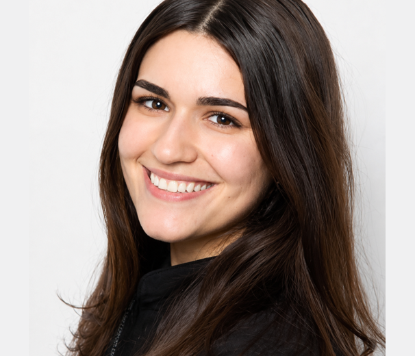 Woman with long dark hair smiling at camera against white background