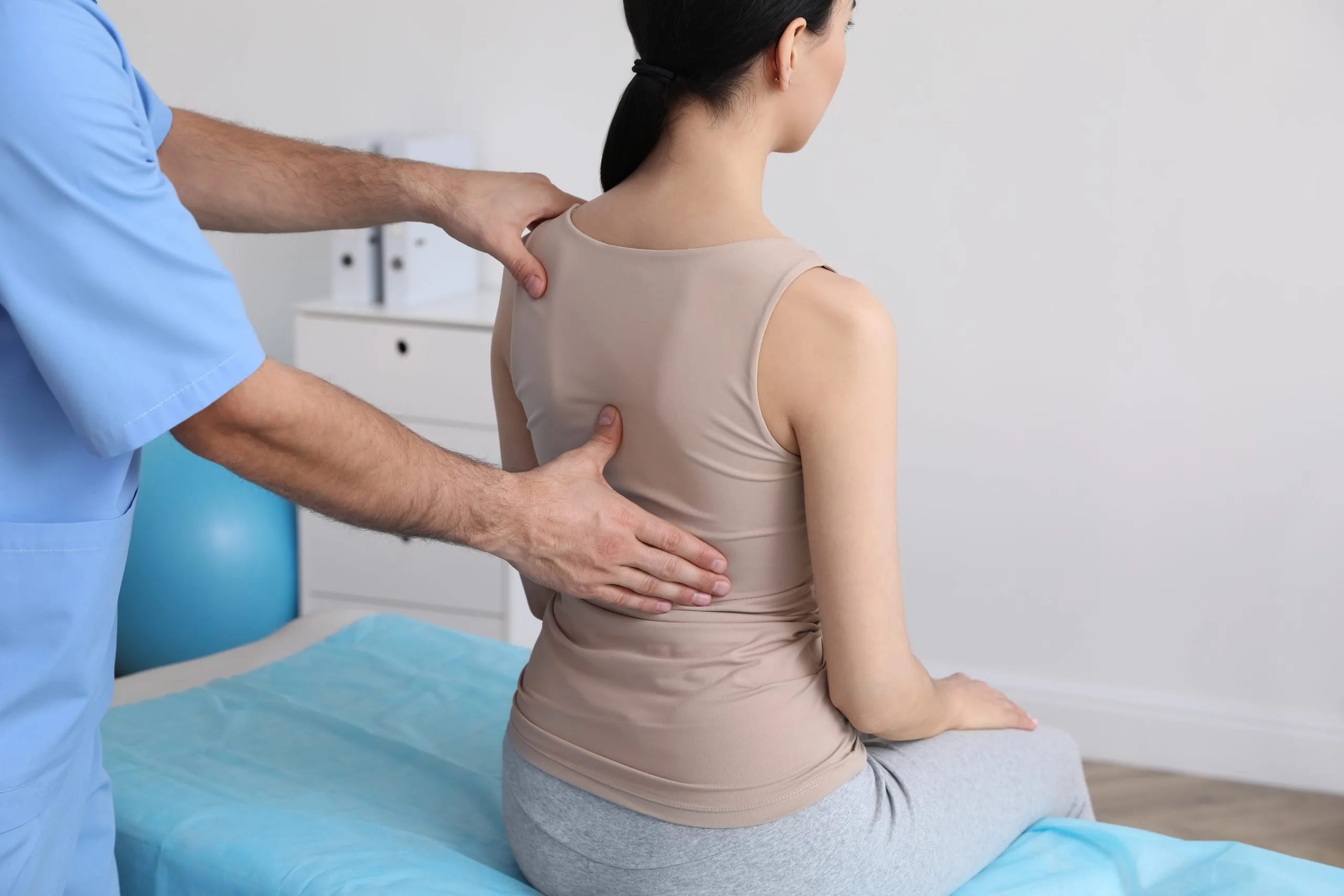 Chiropractor examining patient's spine and back on treatment table