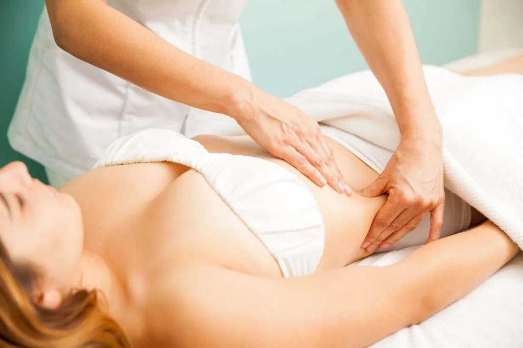 Aesthetic practitioner performing lymphatic massage on patient's leg during body treatment