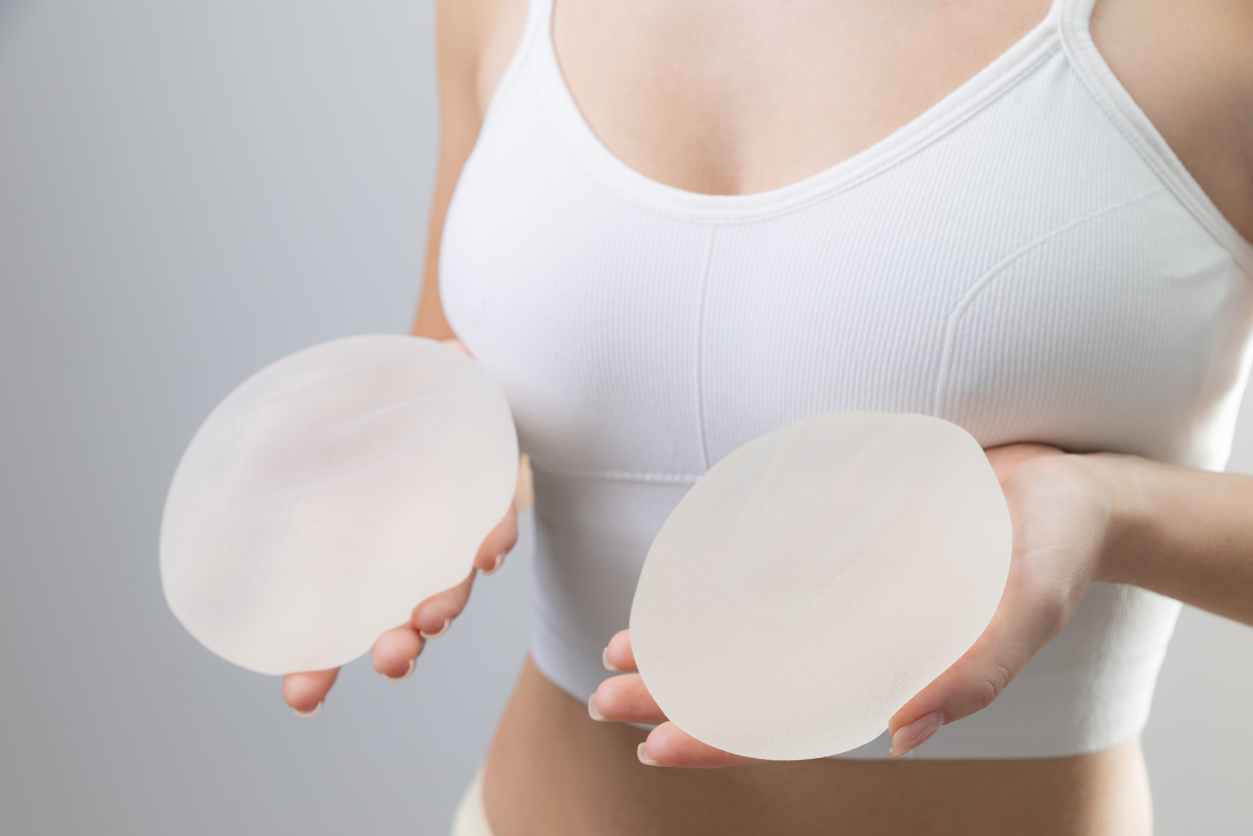 Woman holding two silicone breast implants