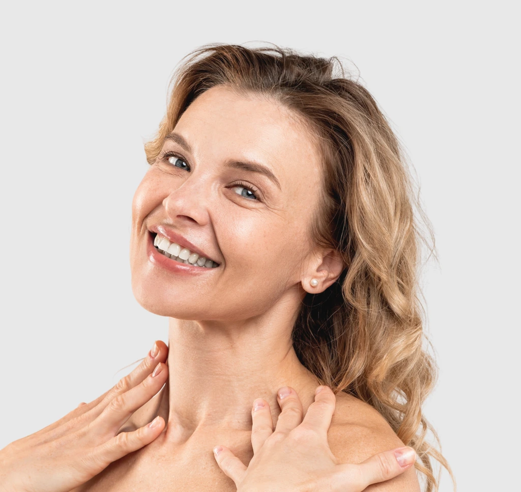 Smiling woman touching her rejuvenated neck and jawline against a neutral background