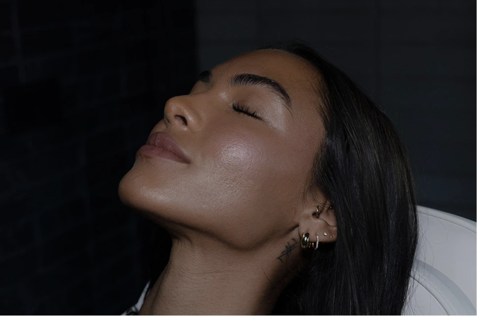 Woman with glowing, clear skin resting her head back with eyes closed