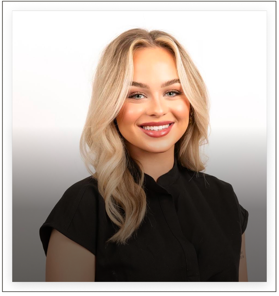 Professional headshot of a team member with blonde wavy hair wearing a black top