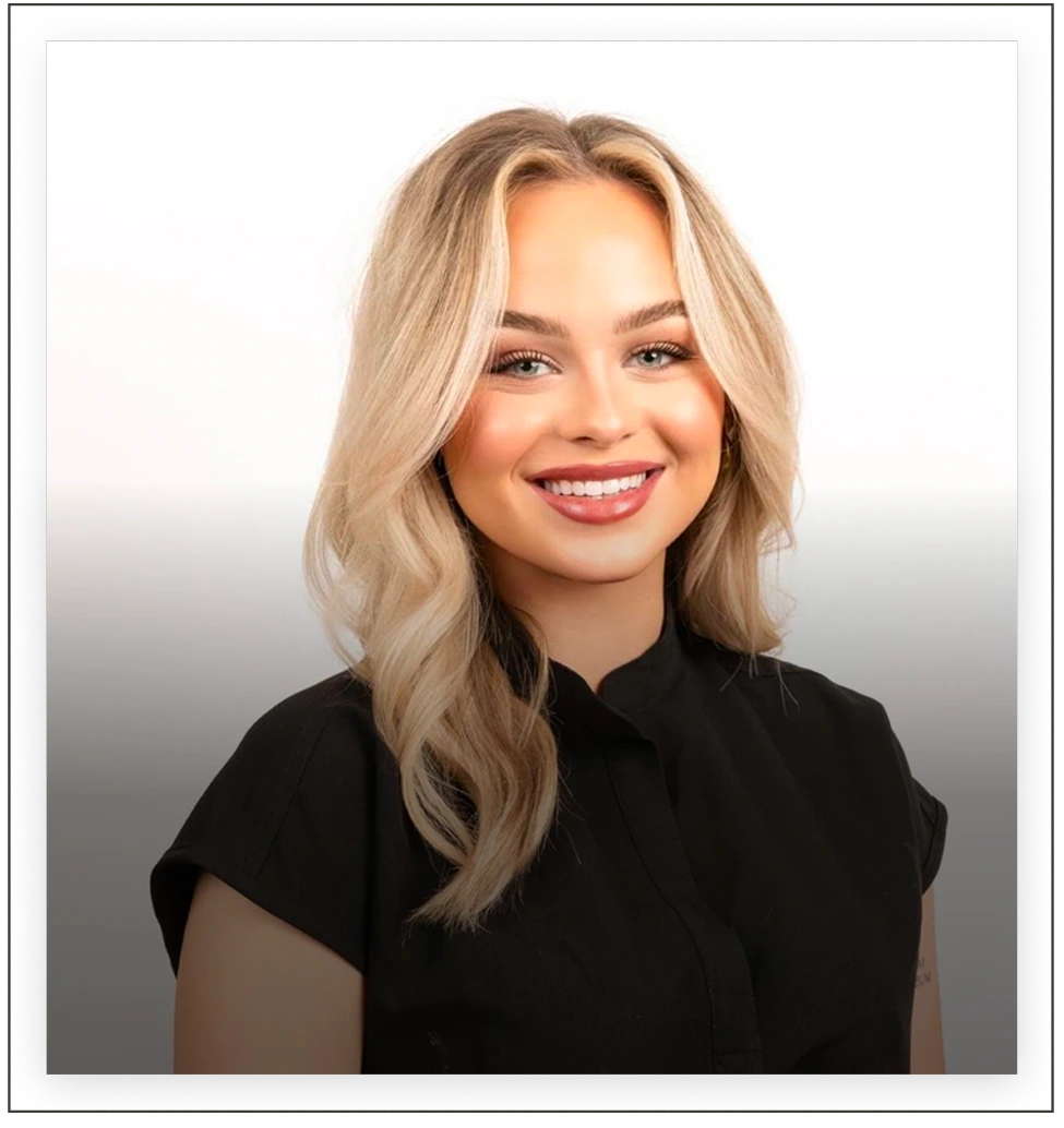 Professional headshot of a team member with blonde wavy hair wearing a black top
