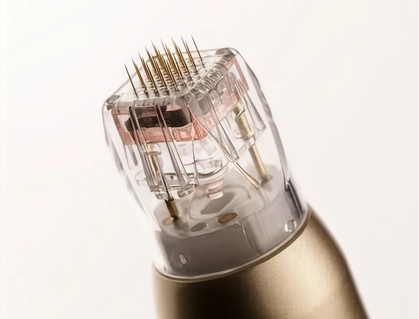 RF microneedling device handpiece with gold-tipped needle cartridge against neutral background