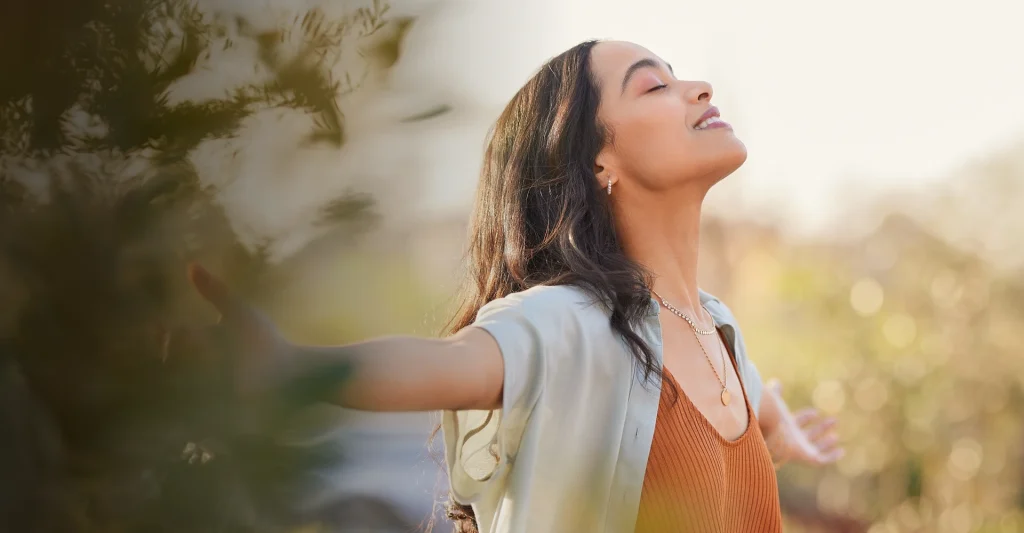 Woman with eyes closed reflecting outdoors in warm sunlight