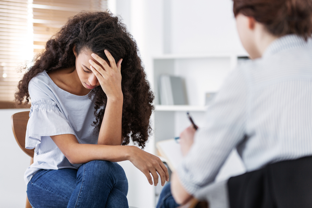 Young woman with her head in her hand talking with a therapist