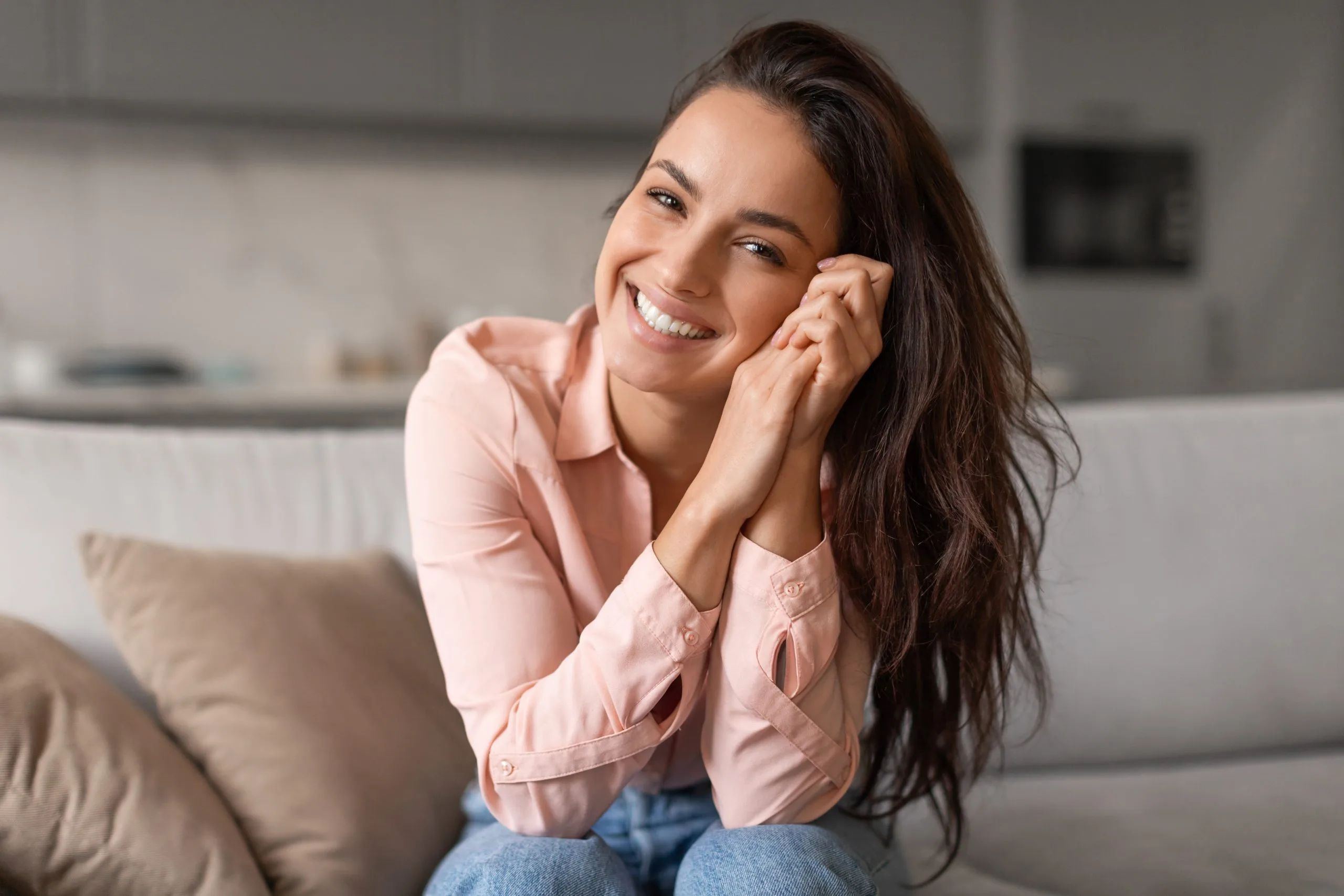 Woman smiling while sitting on a couch at home